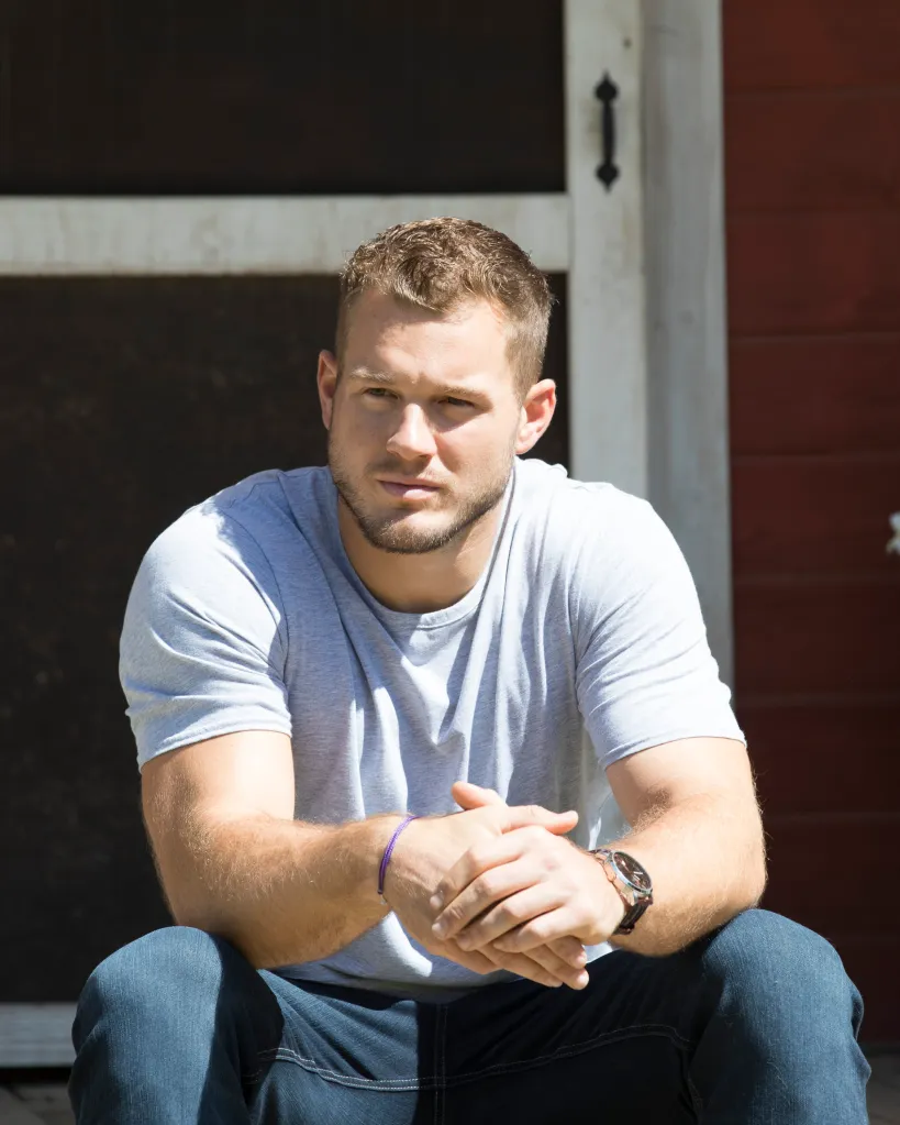 Colton Underwood from "The Bachelor" sits on steps, looking to the side with hands clasped.