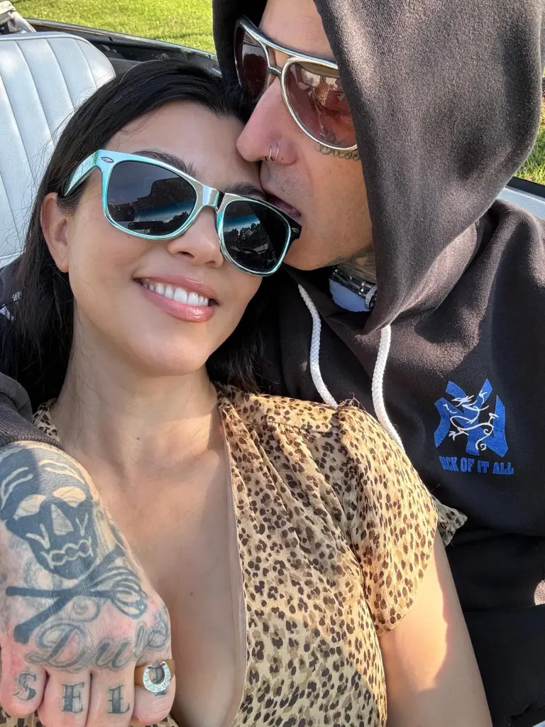 Kourtney Kardashian and Travis Barker embrace in a car.
