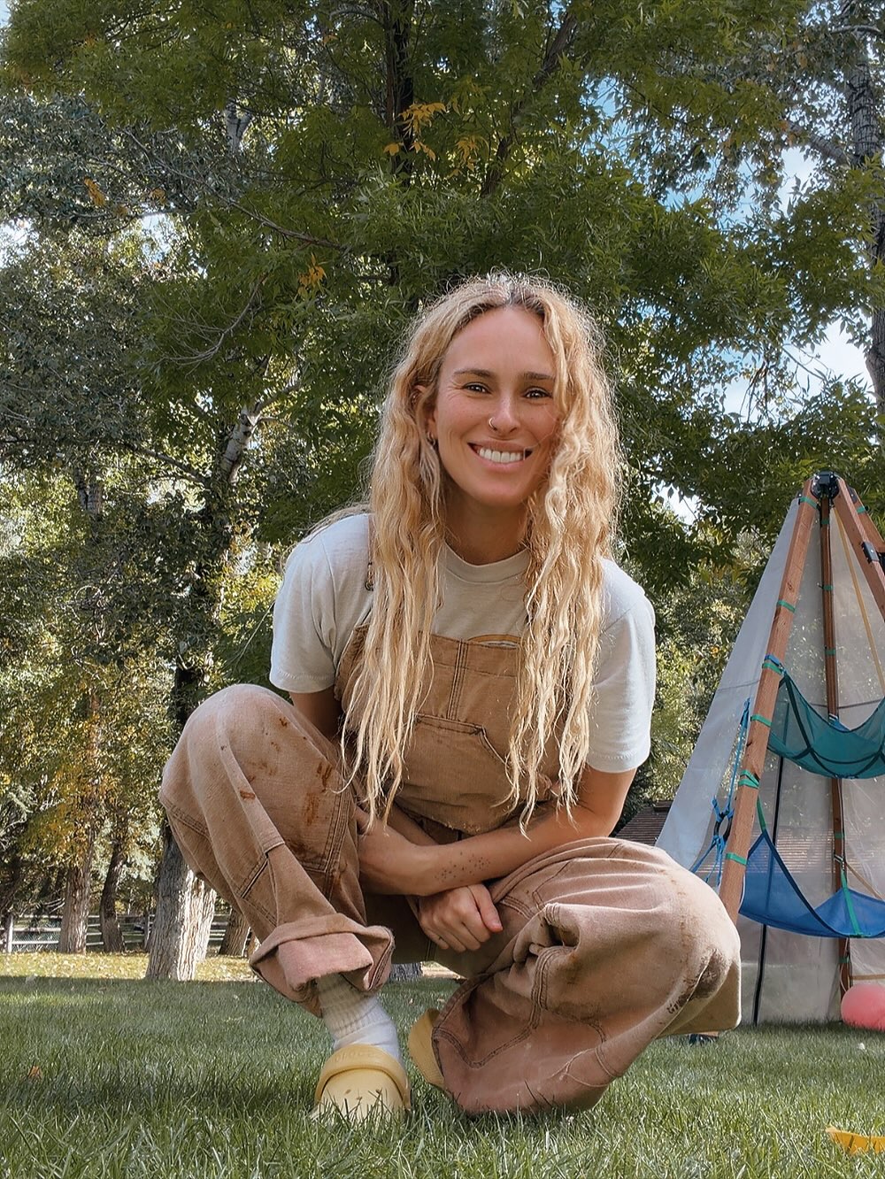 Rumer Willis smiling in dirty overalls in a garden.