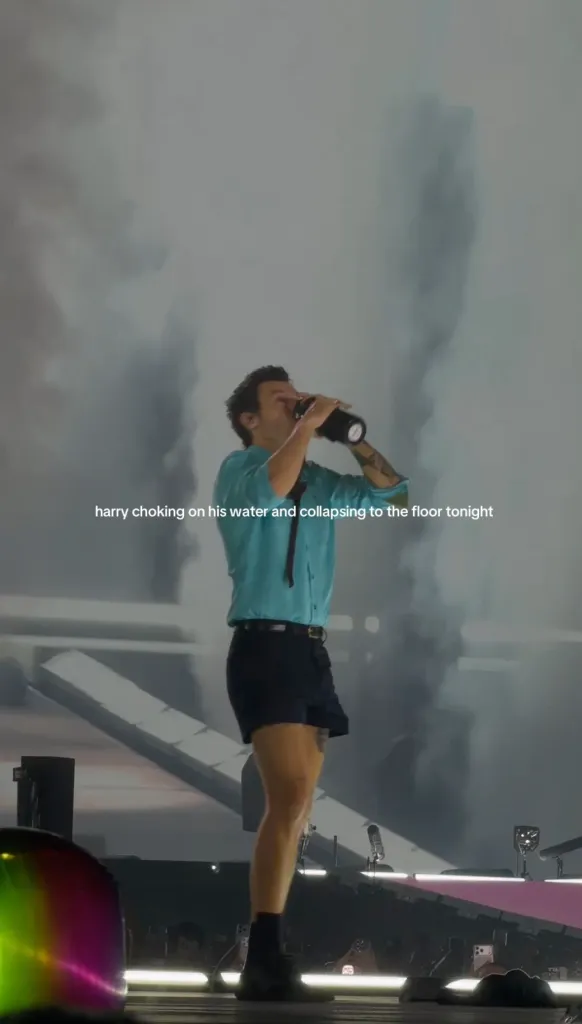 Harry Styles drinking from a bottle on stage, surrounded by smoke, with text overlay "harry choking on his water and collapsing to the floor tonight".