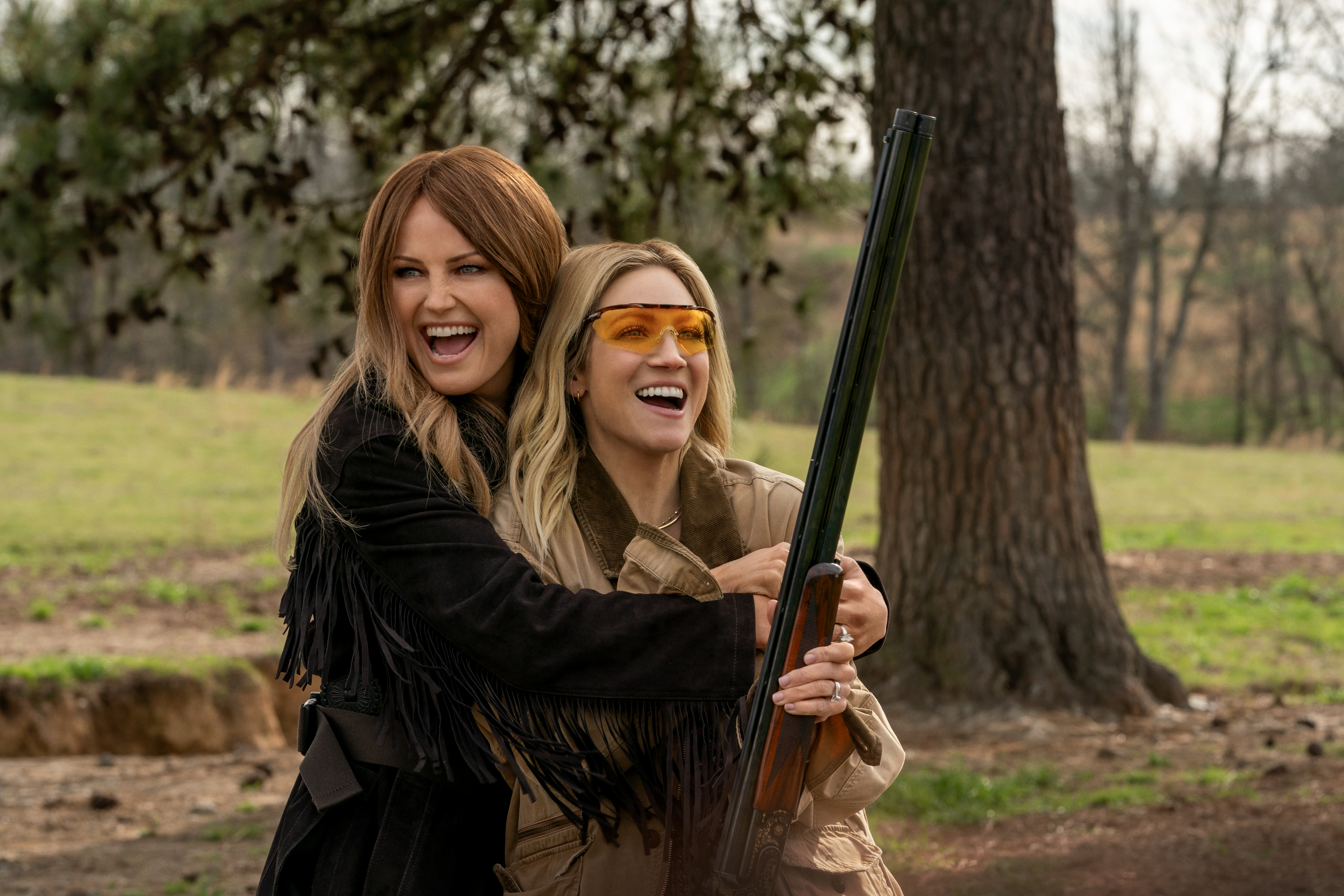 Sophie and Margo laughing while holding a hunting rifle.