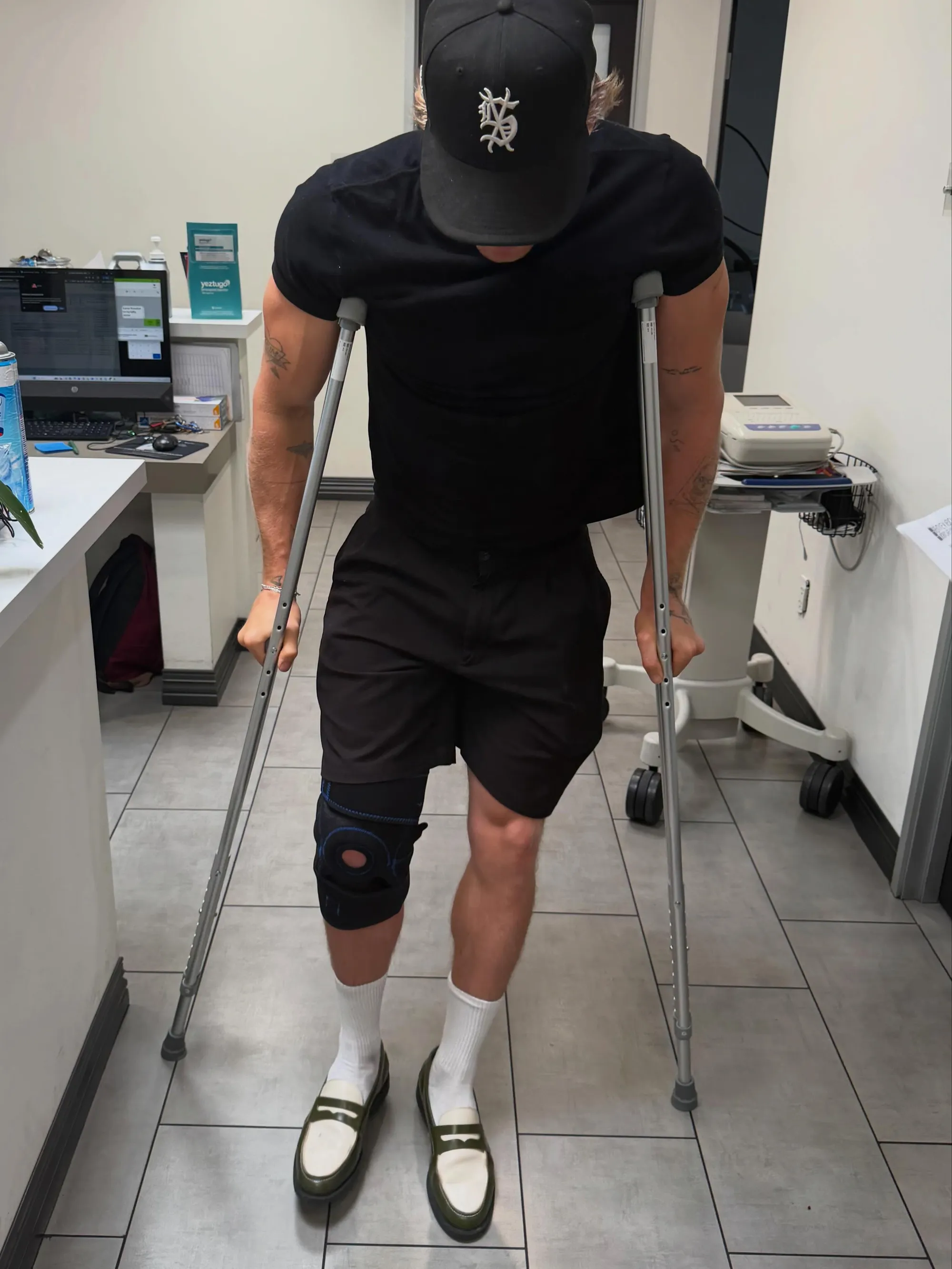 Cody Simpson wearing a knee brace and using crutches.