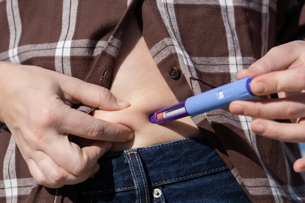 Woman injecting a GLP-1 diabetes treatment into her abdomen with an insulin pen.