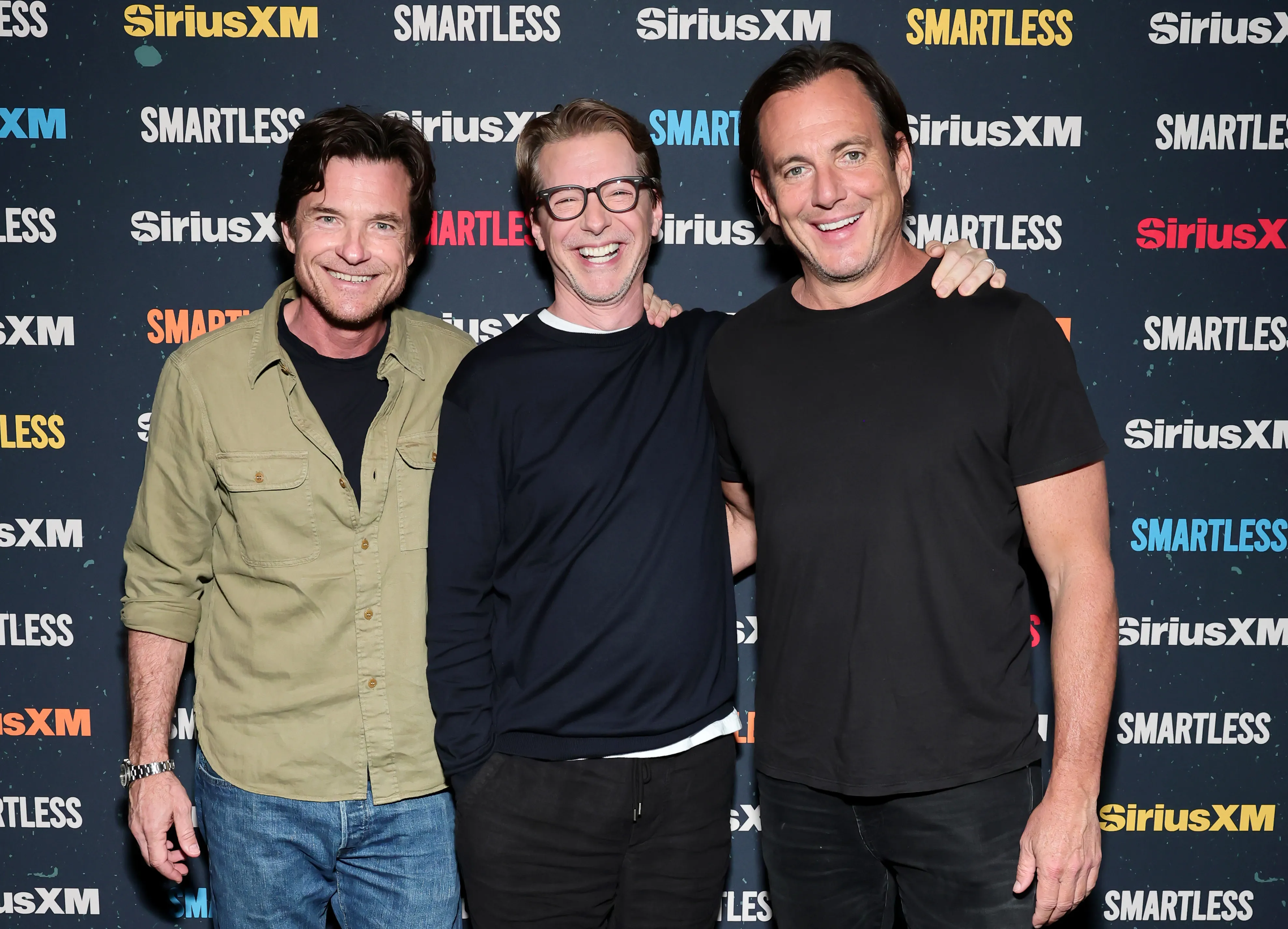 Jason Bateman, Sean Hayes, and Will Arnett smiling at the SiriusXM Presents SmartLess Live event.
