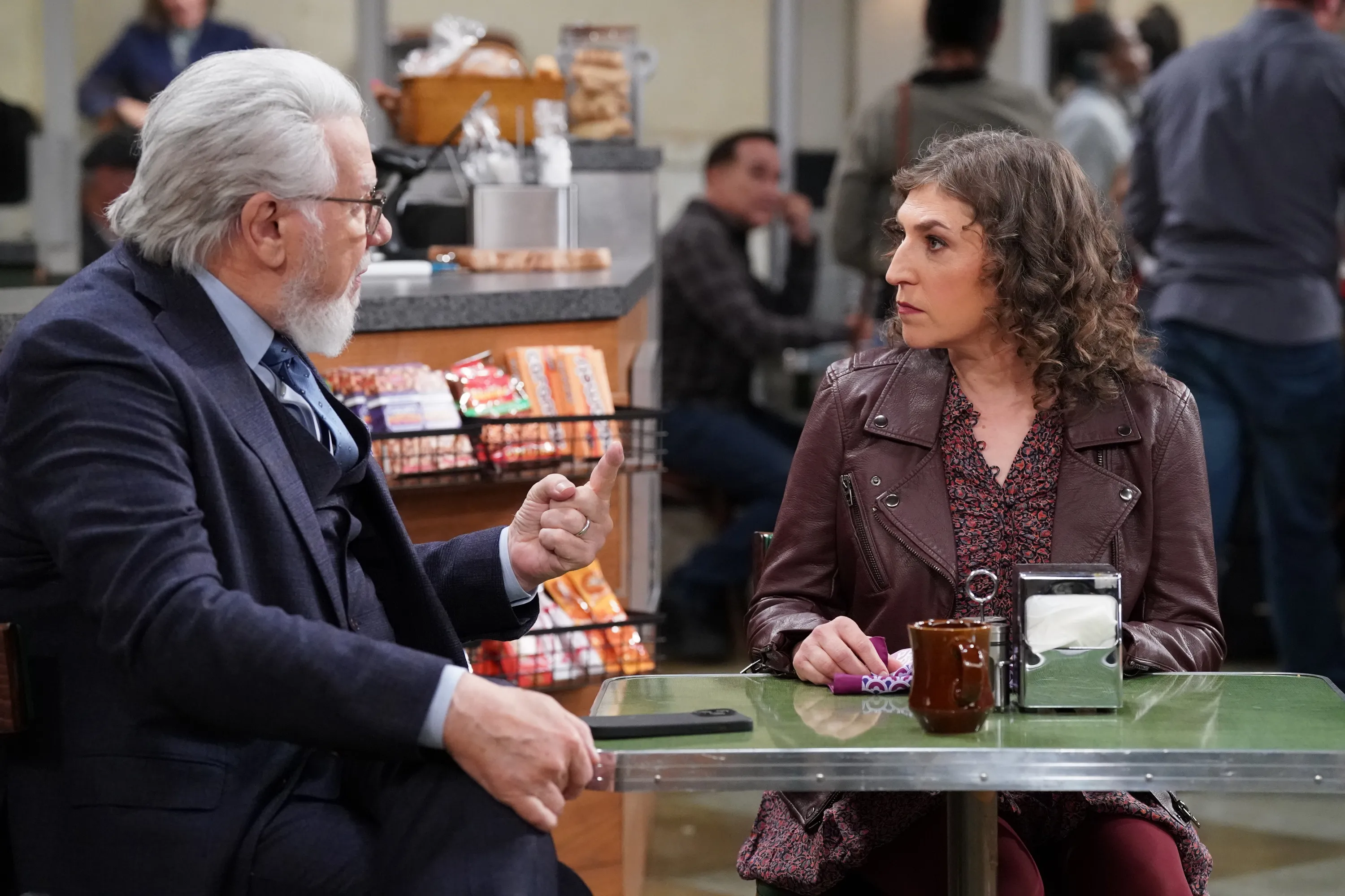 John Larroquette and Mayim Bialik at a diner booth.