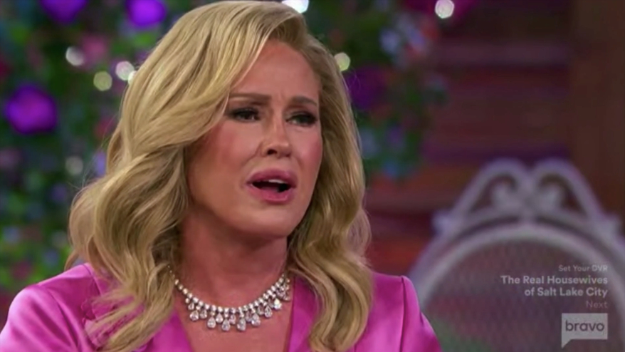 Kathy Hilton in a pink blazer and diamond necklace, with an emotional expression.