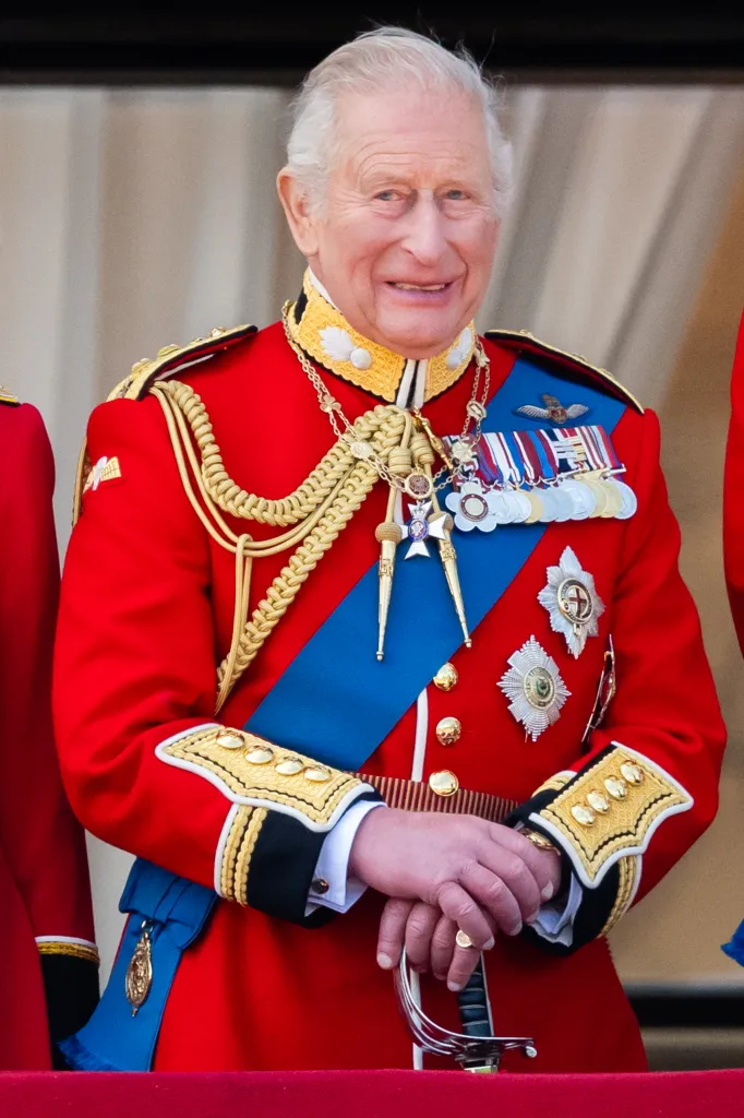 King Charles III smiles while watching an RAF flypast from the balcony of Buckingham Palace.