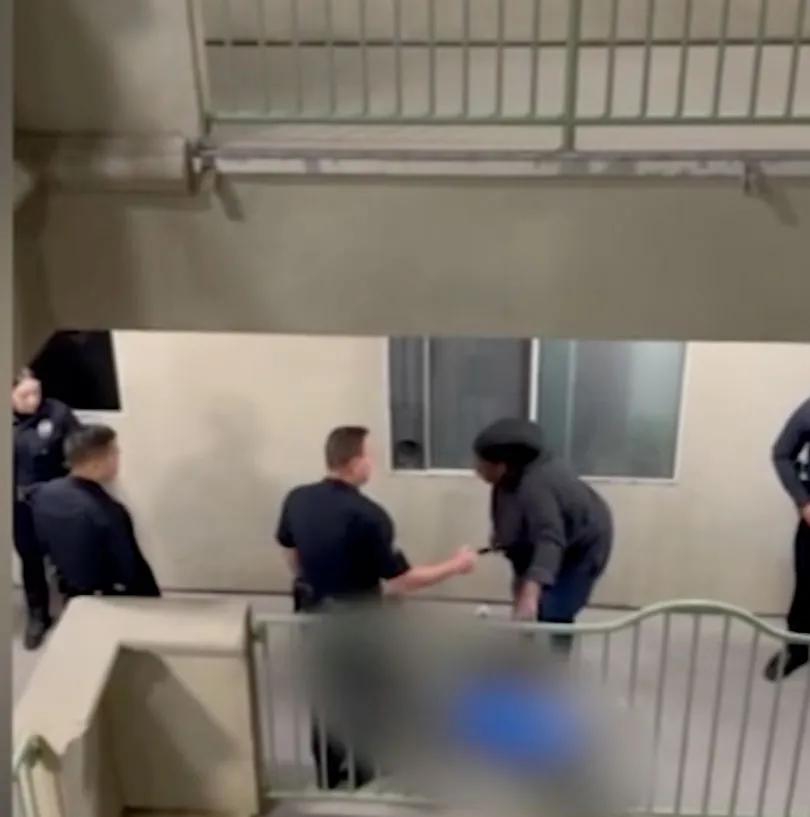 Police officers and a woman gathered around a blurred area on the ground, indicating a tragic event.