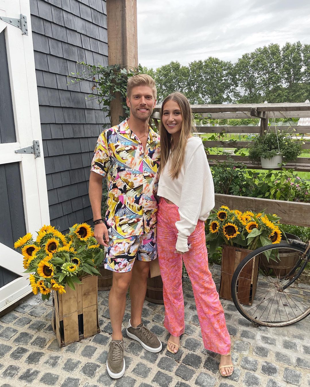 Kyle Cooke and Amanda Batula posing outside.