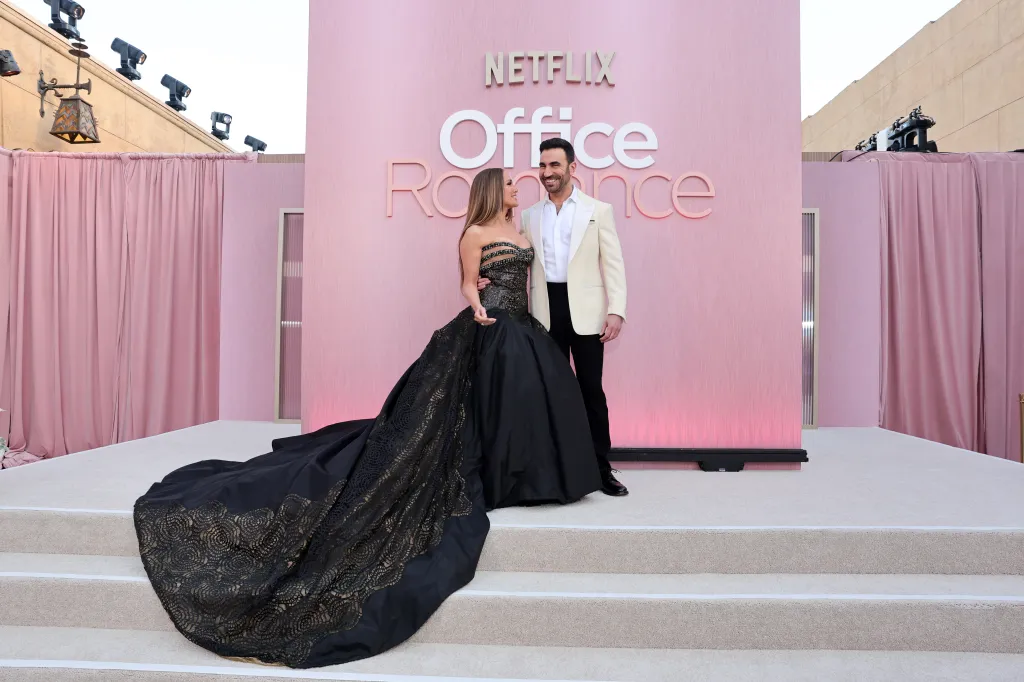 Jennifer Lopez in a black gown and Brett Goldstein in a cream suit at the "Office Romance" premiere.