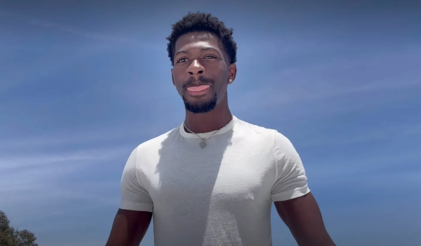 Lil Nas X sticks out his tongue in front of a blue sky.