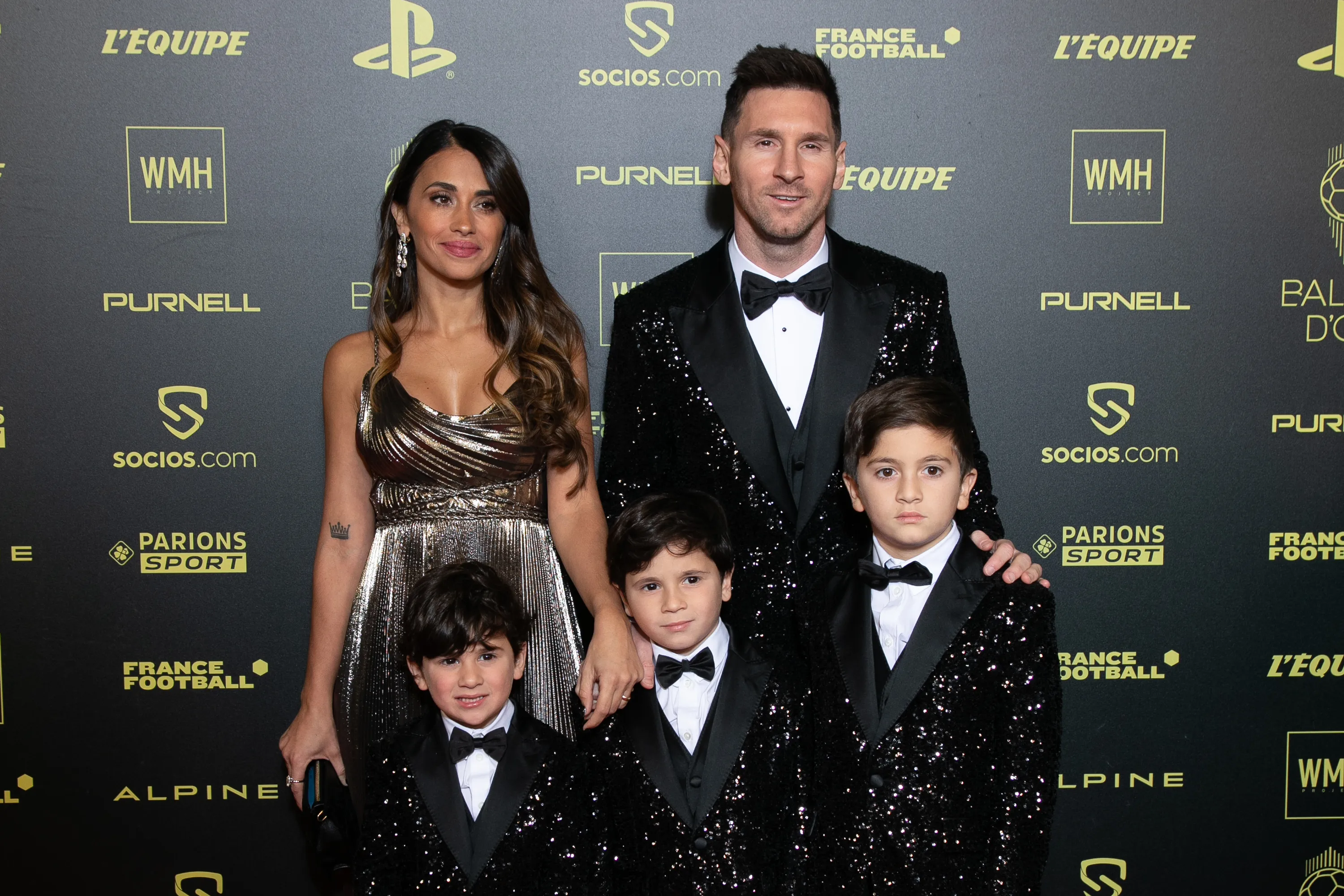 Lionel Messi, Antonella Roccuzzo, and their two sons, Thiago and Mateo, pose on a red carpet at the Ballon D'Or.