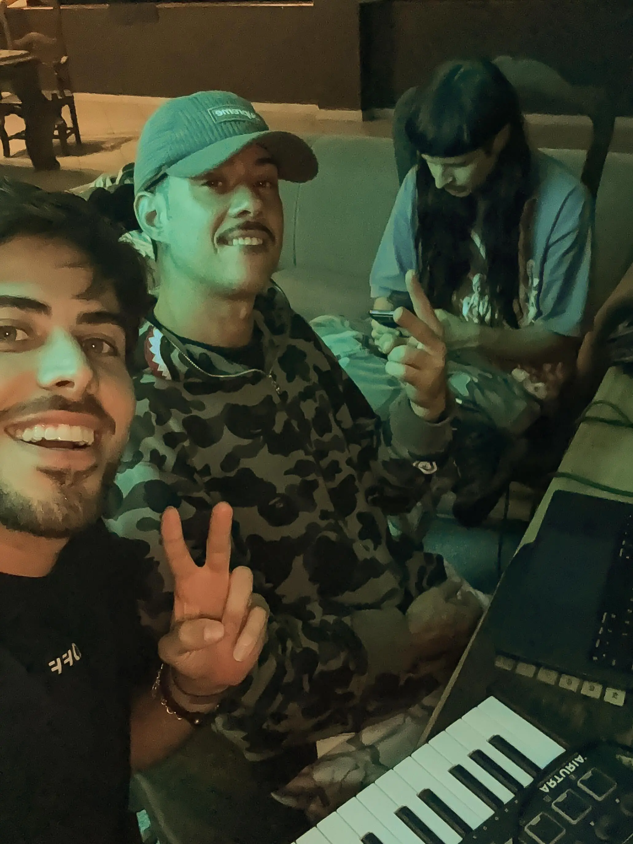 Lucas Frota, Victor WAO, and Oliver Tree smiling and making peace signs, with a keyboard in the foreground.