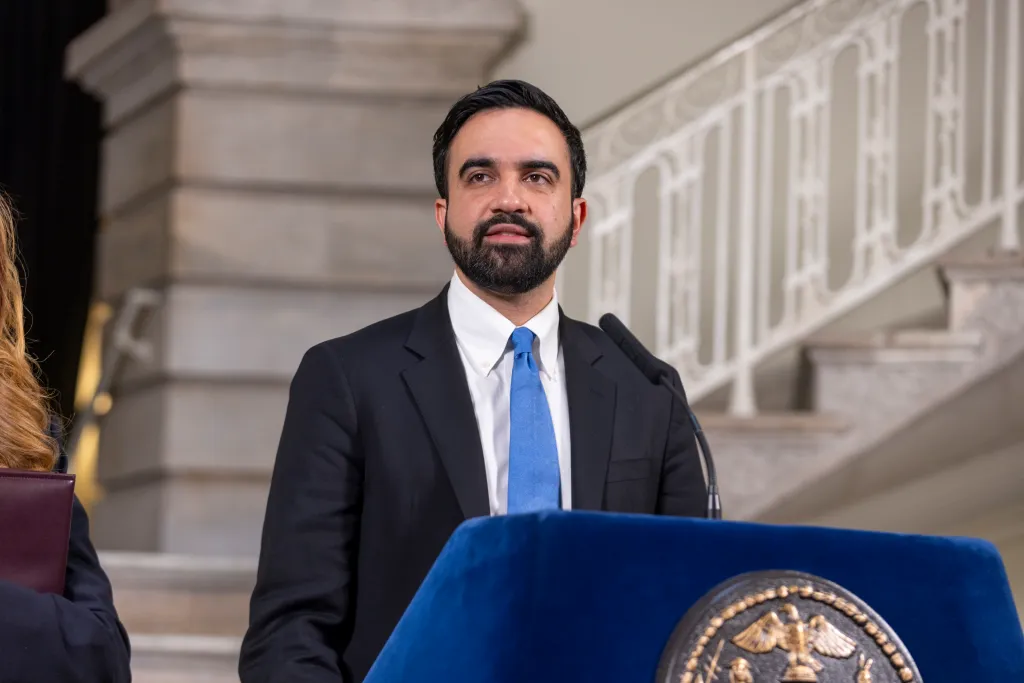 Mayor Zohran Mamdani speaks at a podium to the press at City Hall.
