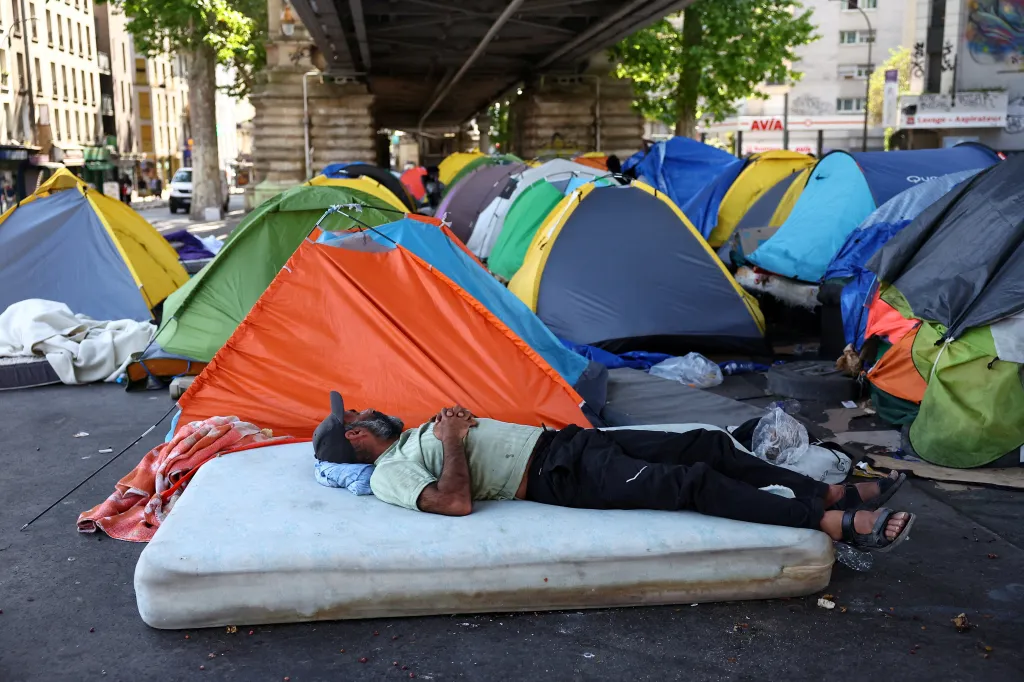 A migrant rests on a mattress outside a row of tents in a makeshift camp in Paris.