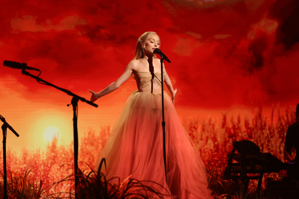 Ariana Grande performing "imperfect for you" in a nude and light pink tulle gown against a red sunset backdrop.