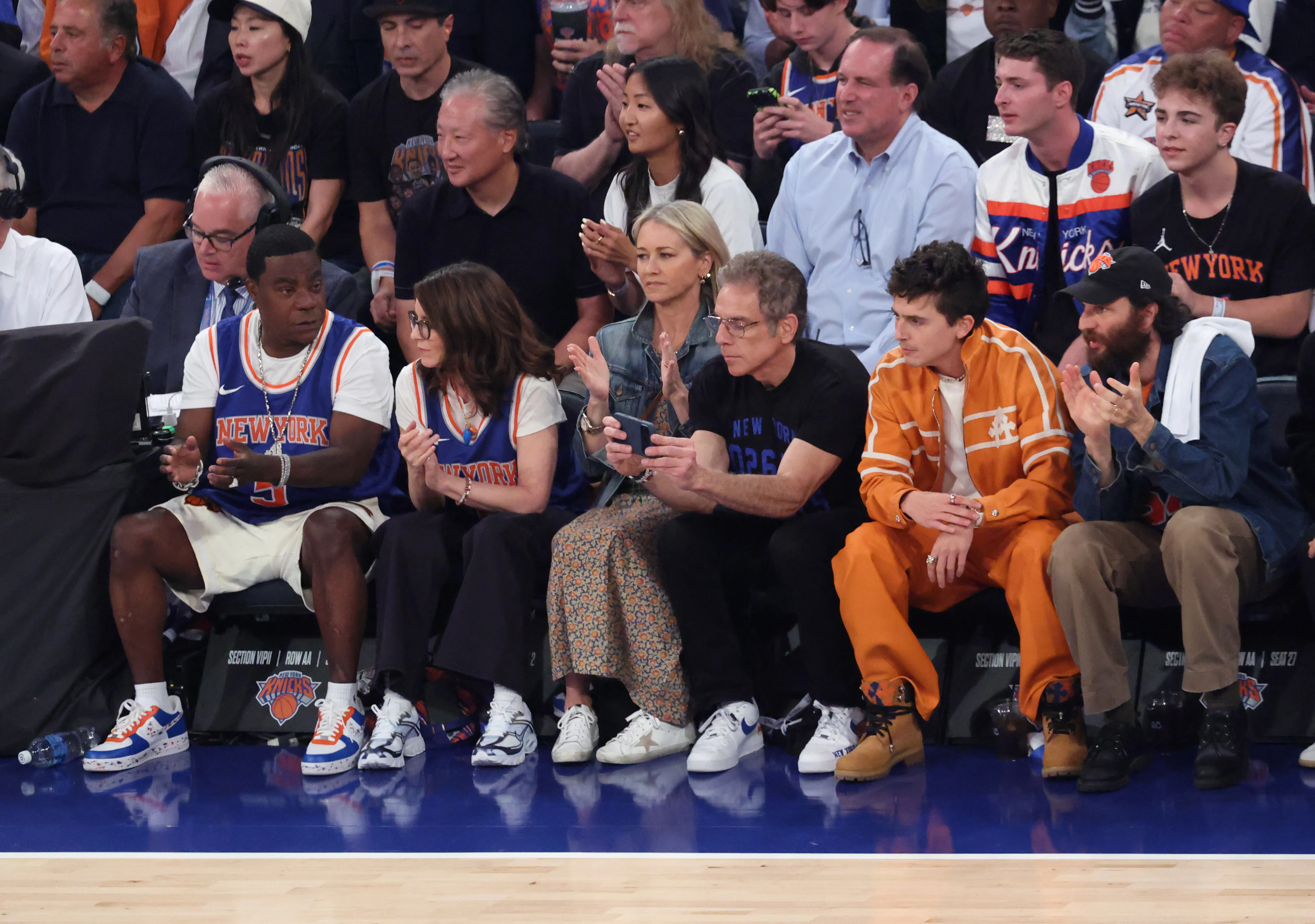 Actors Tracy Morgan, Tina Fey, Christine Taylor, Ben Stiller, and Timothée Chalamet sit courtside during an NBA Finals game.