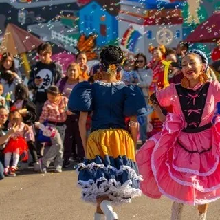 Two girls in festive dresses dancing at the North Fair Oaks Holiday Celebration.