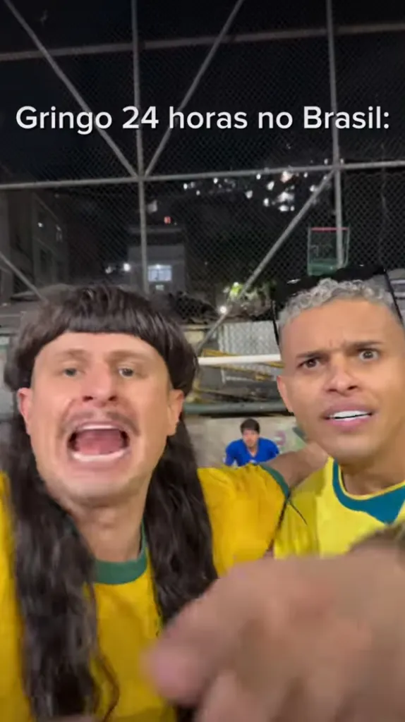 Man in a wig with a mullet and mustache yelling while another man reacts in surprise.