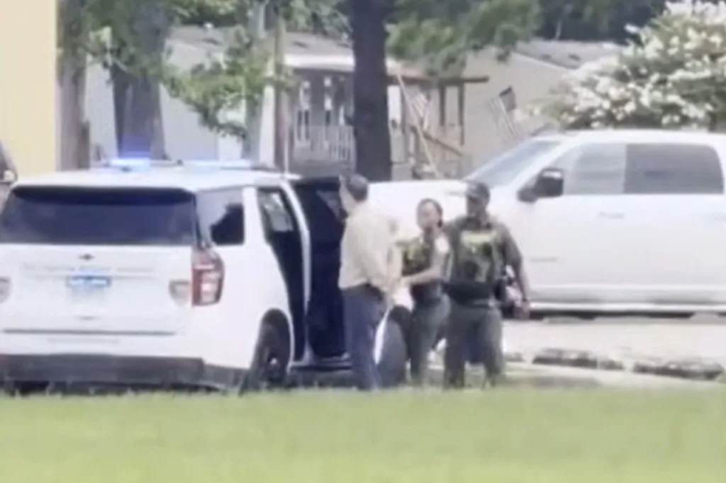 Pastor Tony Spell being arrested and escorted by police to a police vehicle.
