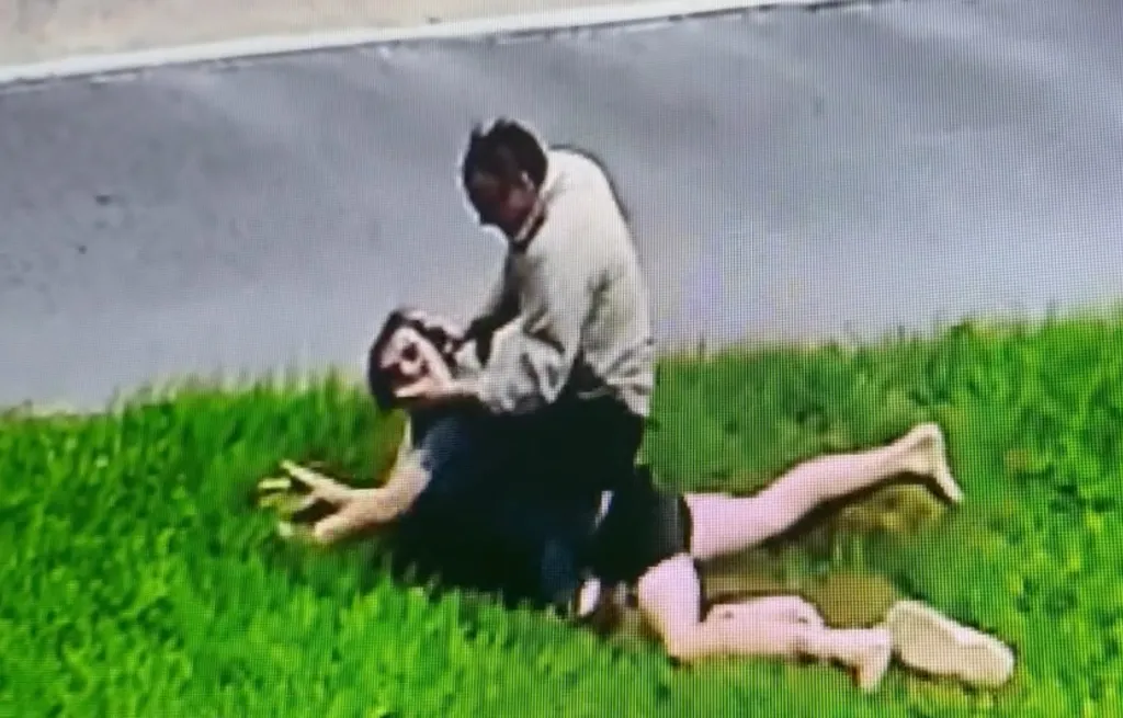 Pastor Tony Spell on top of a man on the grass.