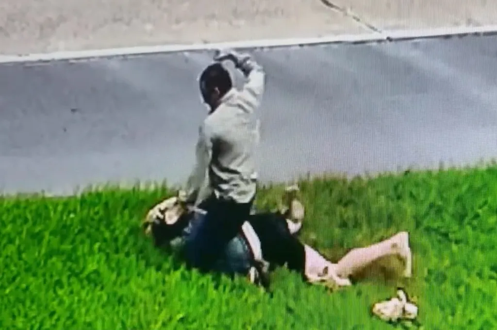 Pastor Tony Spell striking a man lying on the grass.