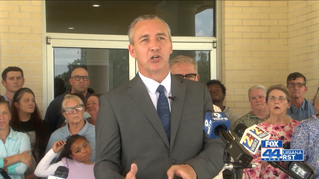 Pastor Tony Spell addresses the media with people standing behind him.