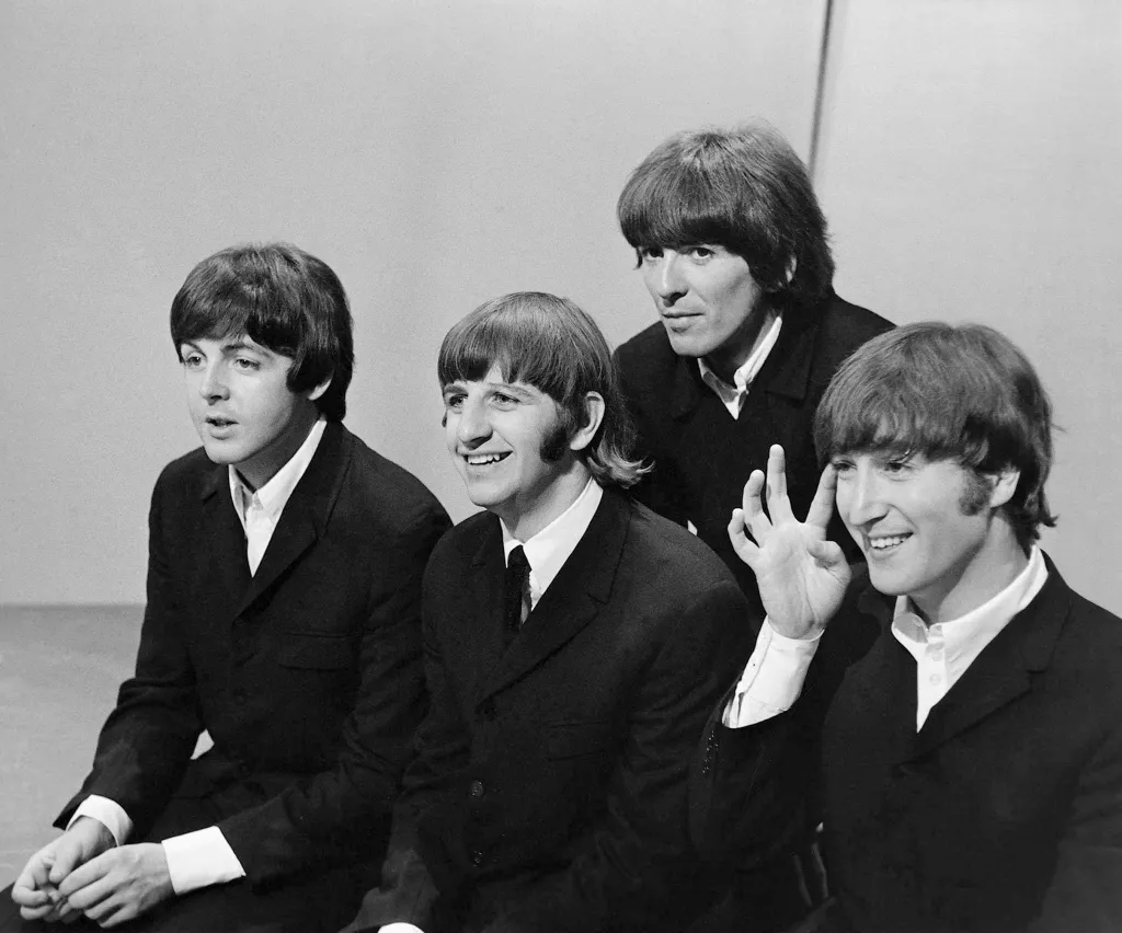 The Beatles smiling and sitting on the set of "Top Of the Pops."