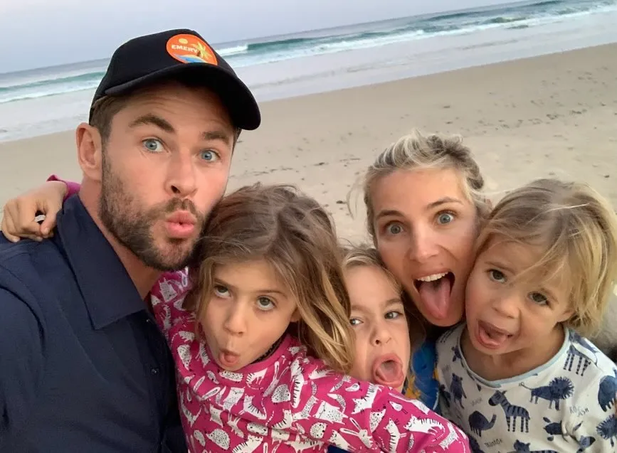 Chris Hemsworth and Elsa Pataky with their three children making silly faces on a beach.