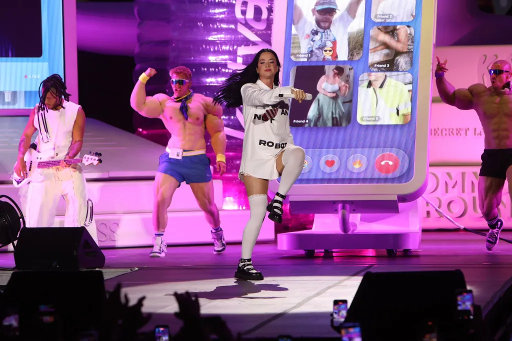 Katy Perry performing at the 'O Son do Camino' festival in Spain, with two bodybuilder dancers and a bassist.