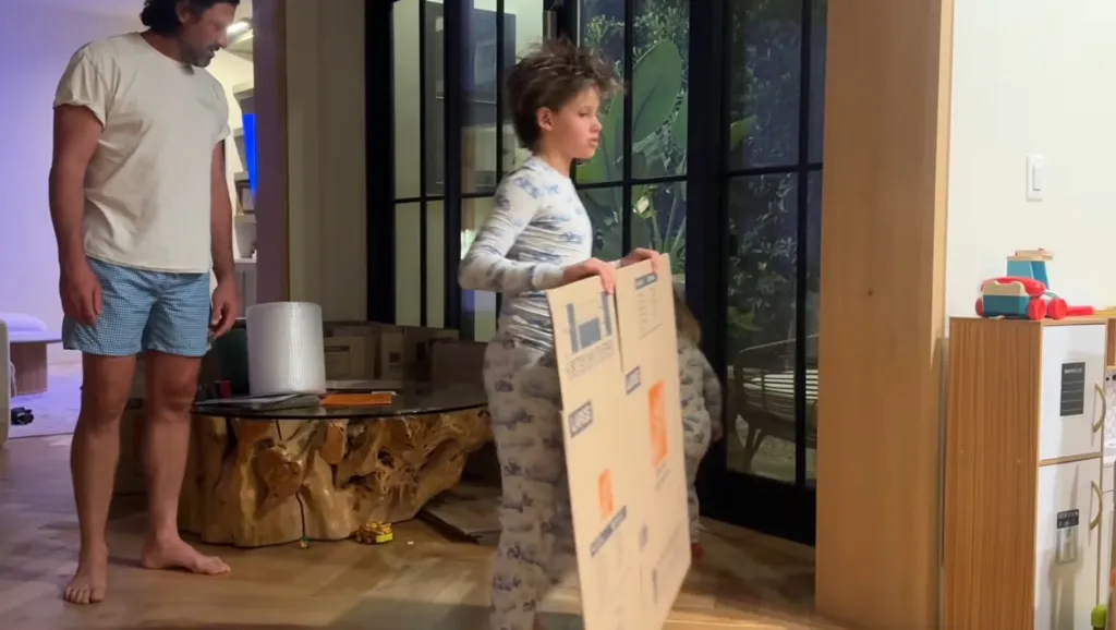 Maksim Chmerkovskiy and Peta Murgatroyd's son Shai moving a cardboard box.