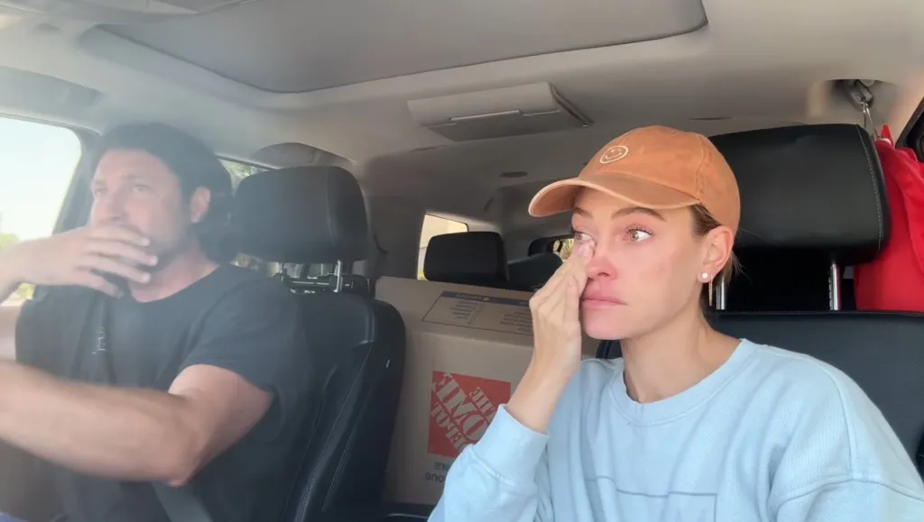 Peta Murgatroyd wiping tears from her eyes as she and Maksim Chmerkovskiy drive with moving boxes in the back.