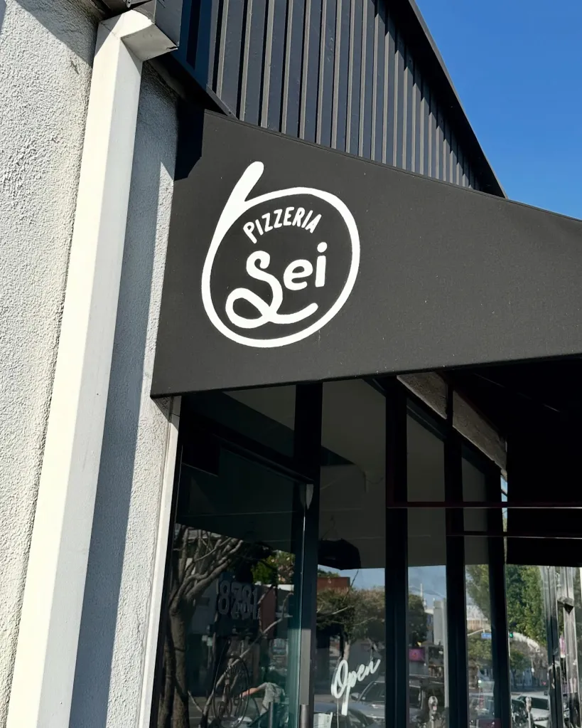 The Pizzeria Sei sign on a black awning over the restaurant's entrance.