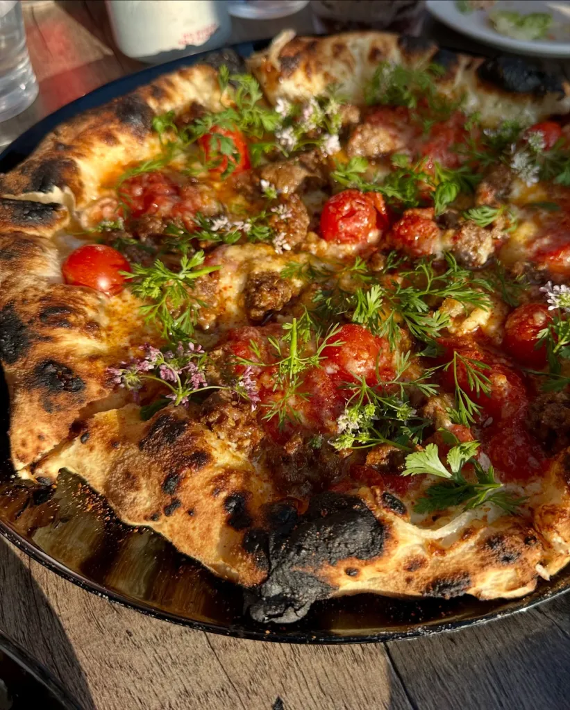 Pizza Sei with meat, cherry tomatoes, and herbs.