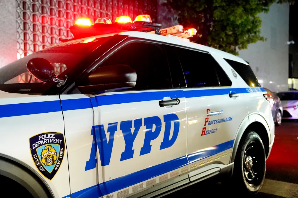 A white NYPD Highway Patrol SUV with blue stripes, emergency lights, and department emblem.