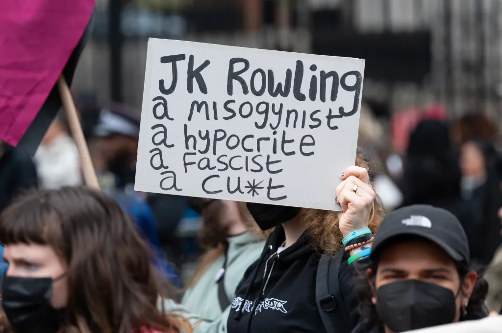 A protester holds a placard reading "JK Rowling a misogynist, a hypocrite, a fascist, a cu*t" at a counter-demonstration in Westminster.