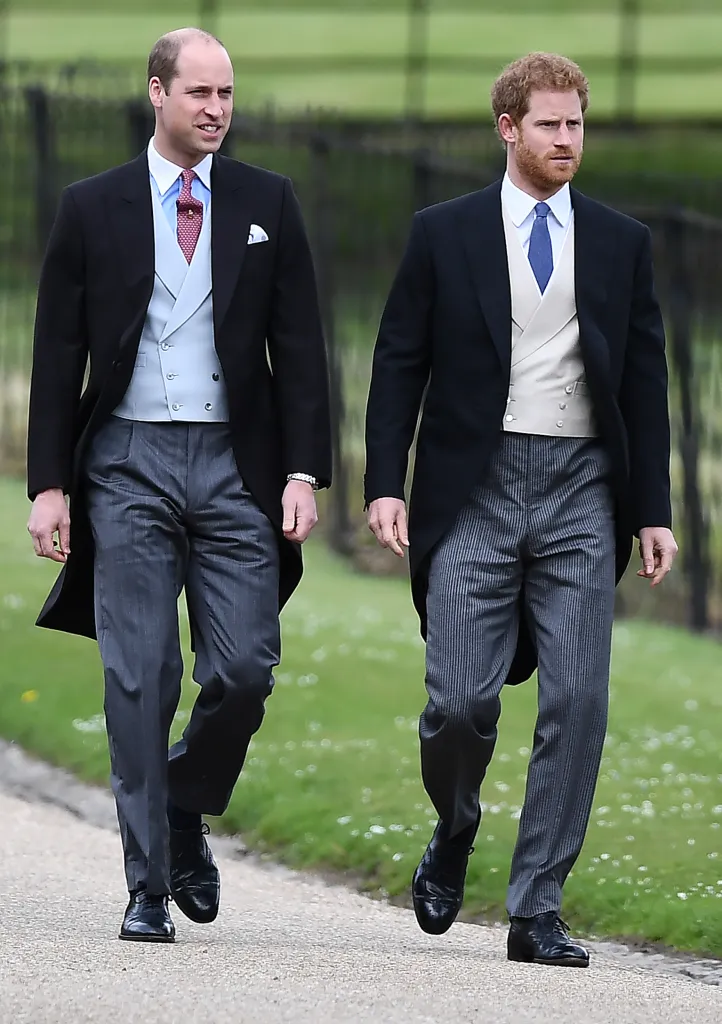 Prince William and Prince Harry walking outdoors in matching formal attire.