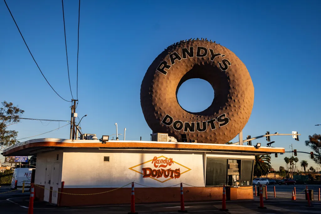 Store with giant donut statue on top of roof.
