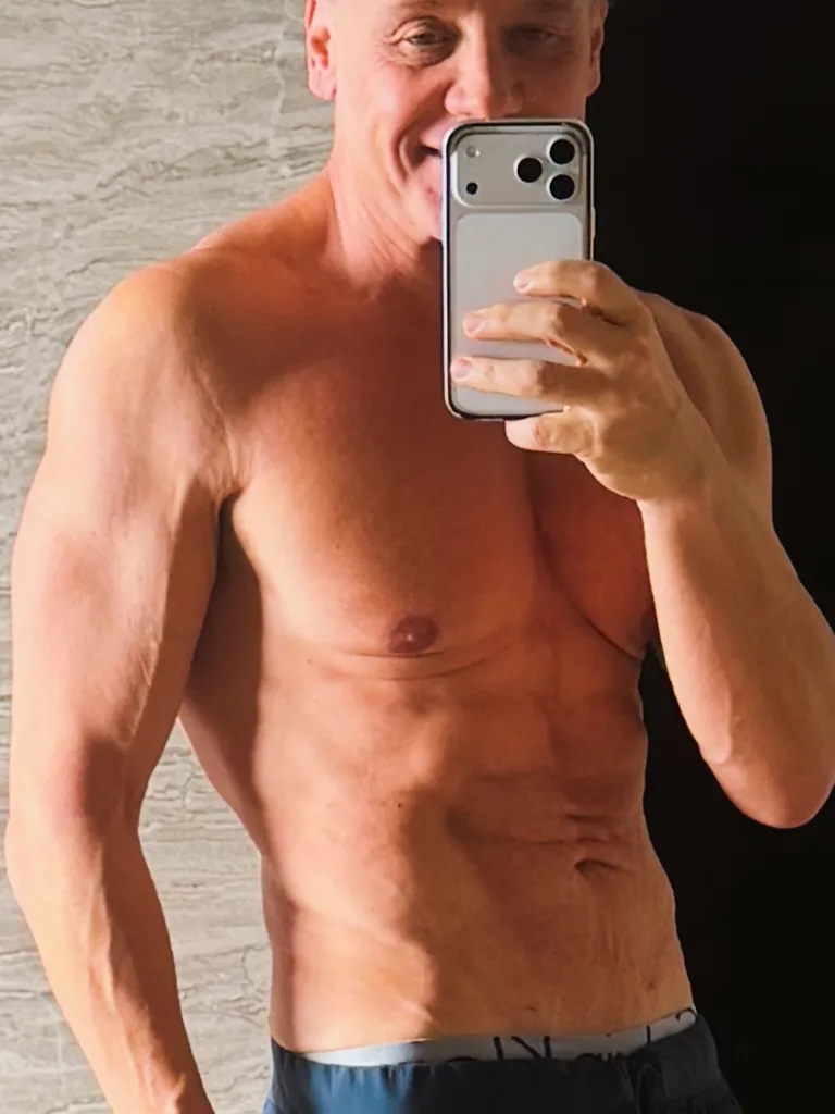 Lenny Hochstein taking a mirror selfie, showing his torso and arm muscles.