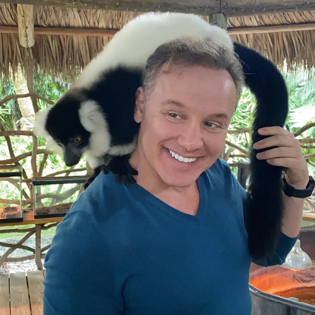 Lenny Hochstein with a black and white ruffed lemur on his shoulders.