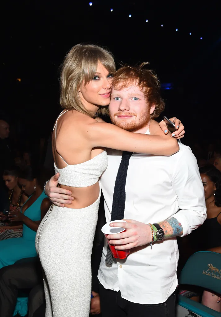 Taylor Swift in a white dress embraces Ed Sheeran in a white shirt and black tie, both looking at the camera.