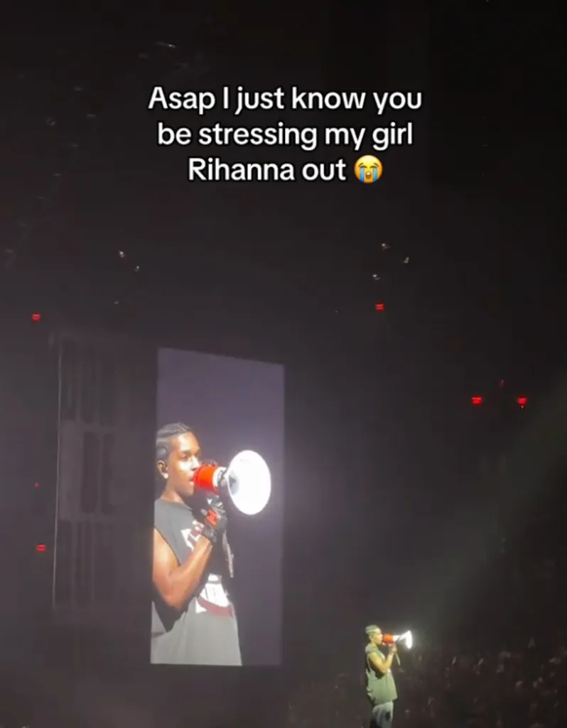 A$AP Rocky on stage using a megaphone in front of a large screen showing his face.