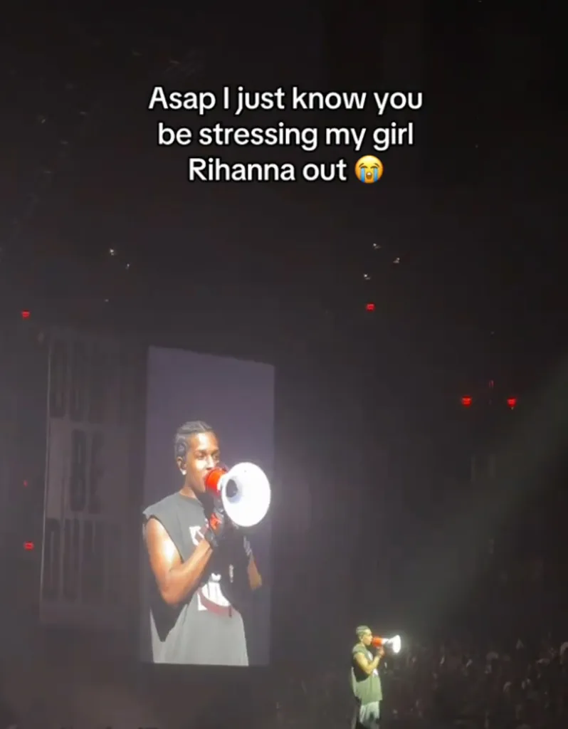 A$AP Rocky on stage at a concert, speaking into a megaphone, with a large screen behind him displaying his image.