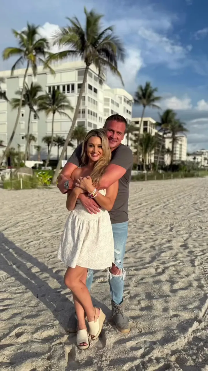 Ryan Lochte and Molly Gillihan embrace on a sandy beach.