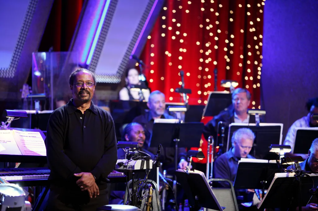 Photo of Harold Wheeler, the piano conductor for "Dancing with the Stars," standing before an orchestra.