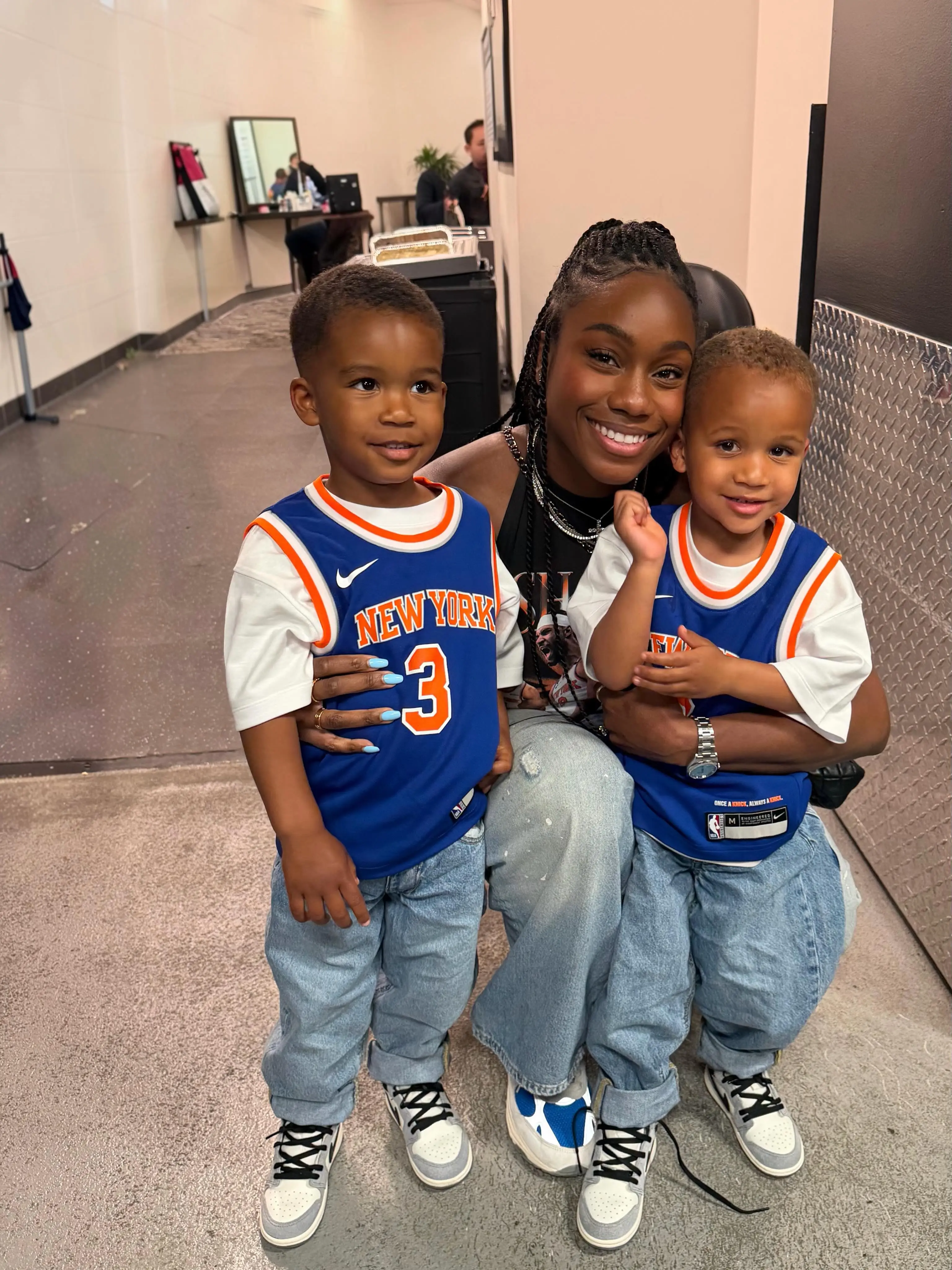 Shannon Hart posing with two children wearing New York Knicks jerseys.