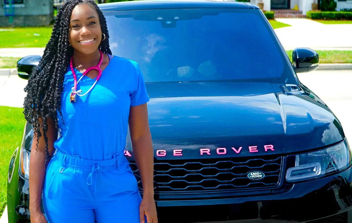 Shannon Hart, dressed in blue scrubs and a pink stethoscope, poses next to a black Range Rover.