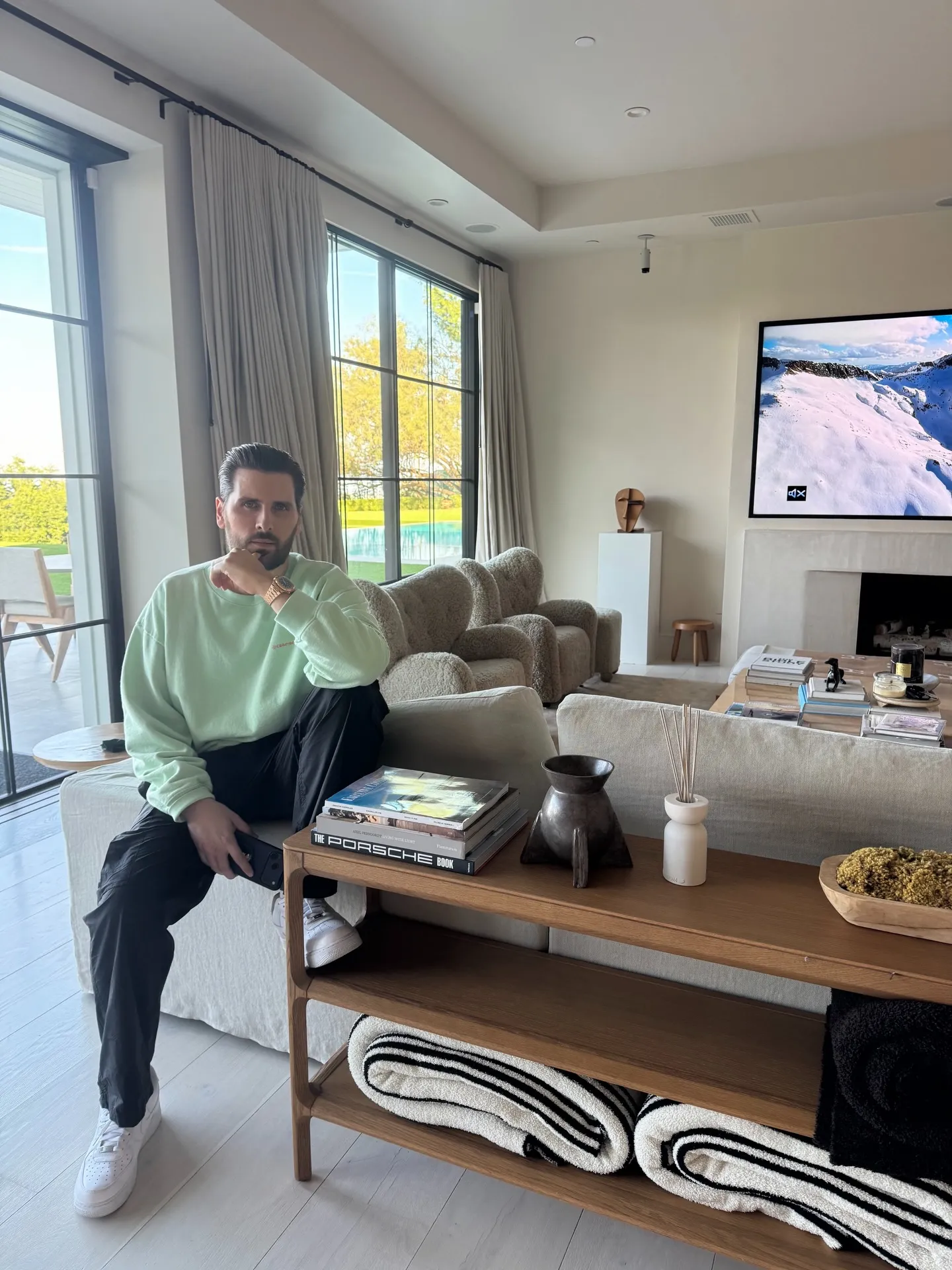Scott Disick seated on a sofa in a spacious living room.