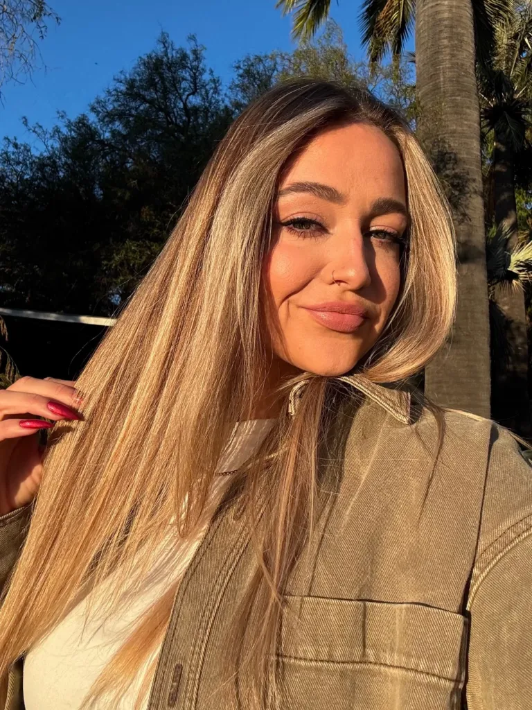 Sydney Pitt, Brad Pitt's niece, smiling in a selfie outdoors.