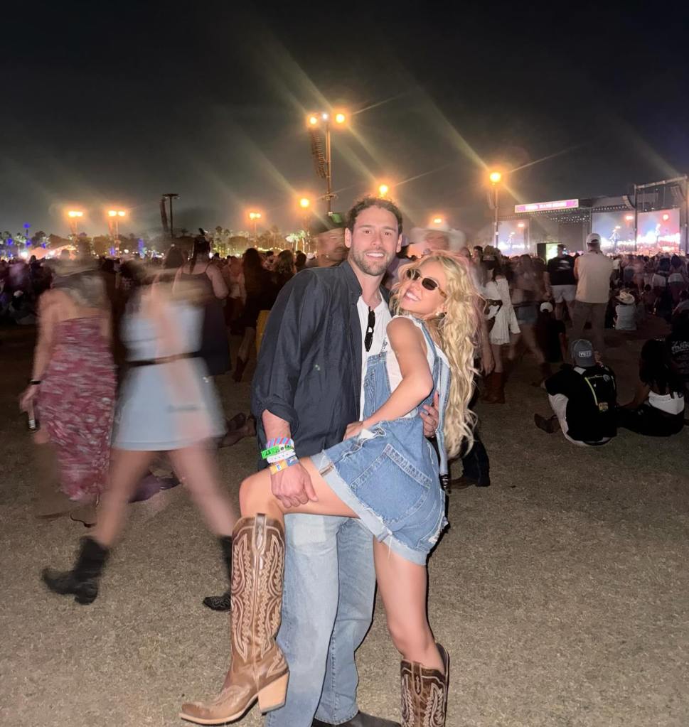Sydney Sweeney in denim overalls and cowboy boots, with a man, at a concert.